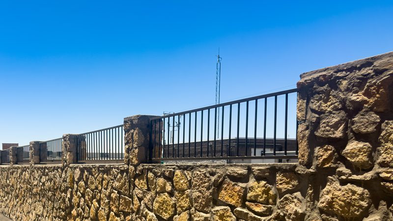 Wrought iron railing set on stone pillars and rock wall